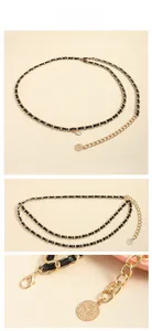 Détail de la ceinture chaîne dorée entrelacée de cuir noir avec pendentif pièce