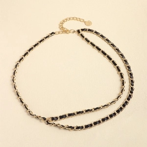 Détail de la ceinture chaîne en métal doré et cuir noir avec pendentif pièce ronde