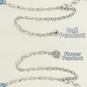 Detail of silver chain extensions featuring ball and hollow flower pendant charms