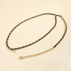 Détail de la ceinture en chaîne dorée et cuir avec fermoir mousqueton et pendentif
