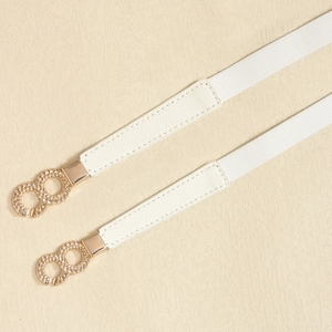 Close-up of white elastic waist belt with textured gold metal infinity buckle detail