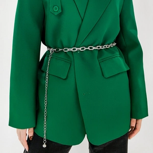 Detail of silver metal chain belt with spherical pendant on green blazer