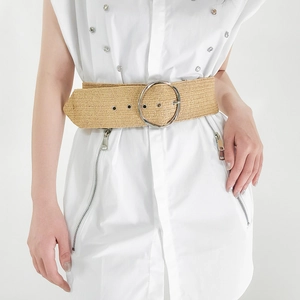 Khaki woven straw belt with a round silver buckle shown on a white shirt