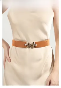 Close-up of brown elastic waist belt with gold mushroom buckle on a stylish dress