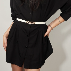 Close-up of white leather elastic belt with golden triple ring buckle on a black dress