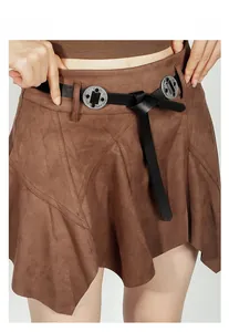 Gros plan d'une boucle en métal gravé sur une ceinture noire avec une jupe en daim marron