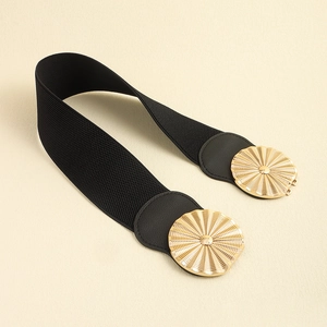 Détail de la ceinture noire élastique avec boucle ronde dorée à motif solaire