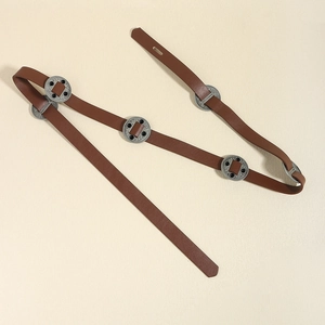 Détail d'une ceinture vintage en cuir marron avec boucles en métal sculpté et inserts