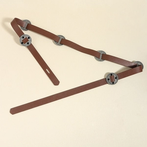 Détail de ceinture en cuir marron avec disques en métal argenté et perles noires