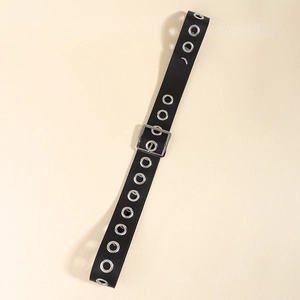 Detail shot of black punk belt with silver metal eyelets and a square pin buckle