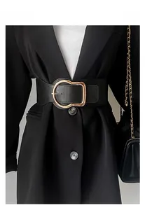 Détail d'une large ceinture élastique noire avec une boucle dorée en fer à cheval