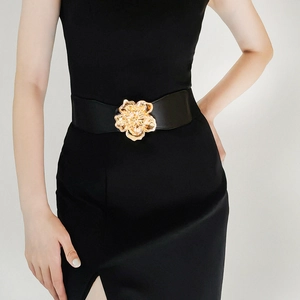 Detail of wide elastic black belt with large golden flower buckle on a dress