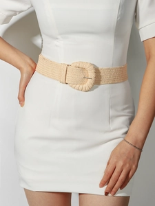Detail of khaki woven straw belt with a large round buckle styled on a white dress