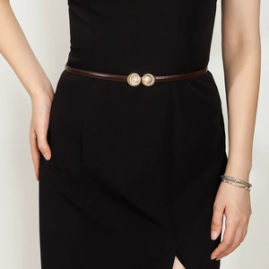 Detail of slim brown leather belt featuring golden rings and elegant pearl embellishments