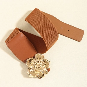 Detail of wide elastic belt featuring a 3D gold metal flower buckle on brown leather