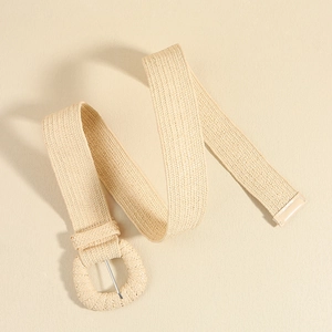 Detailed close-up of khaki woven elastic belt with matching round buckle and metallic pin