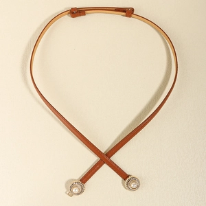 Detail of brown faux leather skinny belt with golden pearl sunflower buckle and stitching