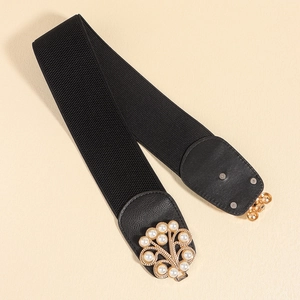 Detailed macro view of golden leaf buckle with inlaid pearls on wide elastic waist belt