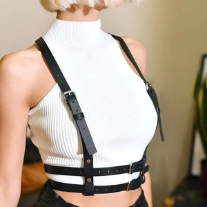 Detail of adjustable black leather body harness with silver metal buckles on white top