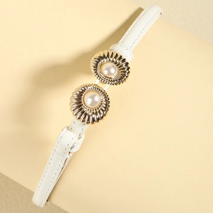 Close-up of white leather belt with gold metal buckle featuring two elegant pearls