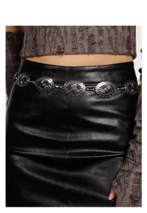 Detail of silver chain belt with sunburst oval plates on a black leather dress