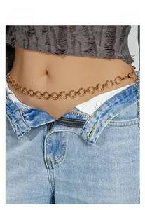 Détail d'une chaîne de taille en métal doré avec anneaux circulaires sur un jean