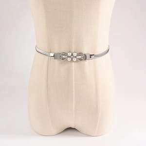 Detail of silver elastic spring waist belt featuring a floral buckle with white pearls