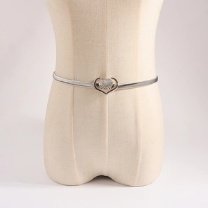 Macro view of silver spring metal waist chain with heart-shaped rhinestone buckle for dresses
