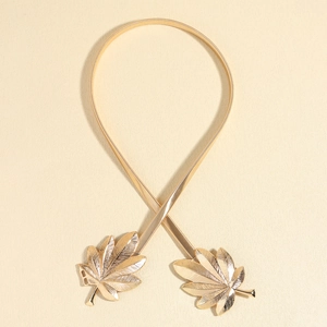 Detailed close-up of golden leaf buckle on elastic metal snake chain belt for dresses