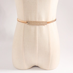Detail of thin gold elastic spring waist chain with rectangular rhinestone buckle