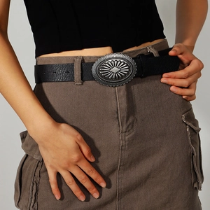 Close-up of a vintage leather belt featuring a large silver engraved floral oval buckle