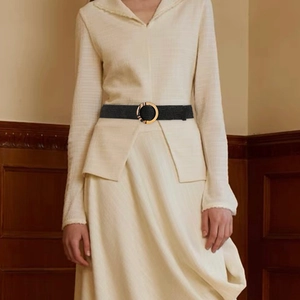 Women's black woven elastic waist belt with a round tortoiseshell buckle on a beige dress