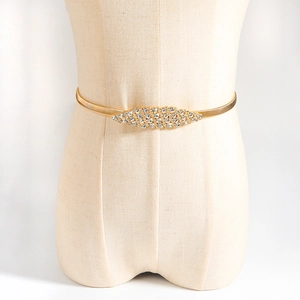 Elegant gold metal spring waist belt with sparkling rhinestone buckle on dress mannequin