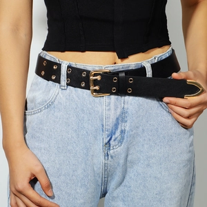 Close-up of black double-eyelet belt with gold pin buckle on blue jeans for women