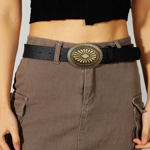 Detailed close-up of a vintage black leather belt with an oval engraved metallic buckle