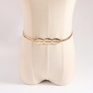 Detailed view of golden leaf buckle on slim elastic metal spring belt for dresses