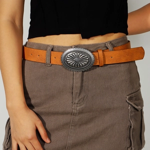 Close-up of brown leather belt with large vintage silver buckle on grey cargo skirt