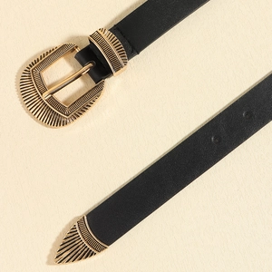 Detail of western vintage engraved gold buckle and tip on a black slim leather belt