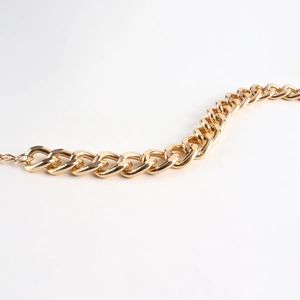 Close-up of golden chunky curb chain metal belt with polished finish on white background