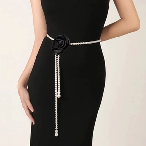 Detailed macro view of an elegant pearl waist chain featuring a black satin rose and tassels