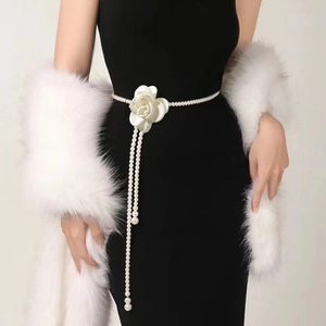 Detail of elegant pearl waist chain with a white fabric rose and tassels on black dress