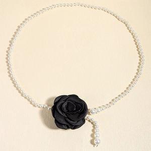 Detail shot of elegant black fabric camellia flower on a white pearl waist chain