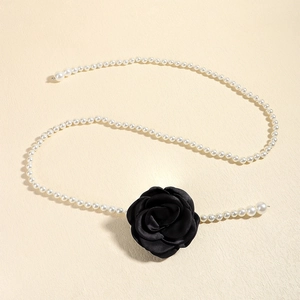 Detail of elegant waist chain featuring white faux pearls and a black satin camellia flower