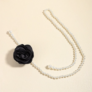 Detail of elegant pearl waist chain with a delicate black camellia flower for dresses