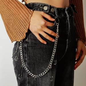 Close-up of punk style silver metal pant chain with safety pins on black denim jeans