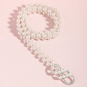 Detail van meerlaagse parelriem met decoratieve zilveren strass-gesp op roze achtergrond
