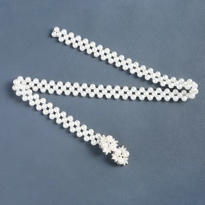 Gedetailleerde macro van de drierijige parelriem met een elegante zilveren bloemengesp