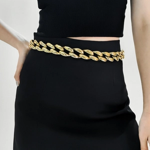 Detail of chunky gold acrylic chain belt on black dress with high metallic luster