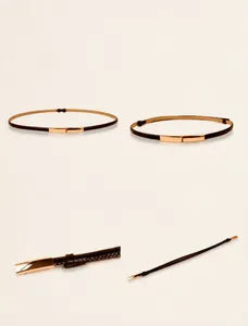 Detail view of the stitching and metallic gold buckle on this slim black waist belt