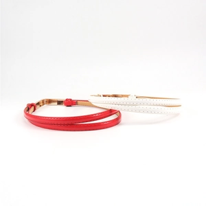 Detail view of glossy red and white leather belts featuring gold minimalist metal buckles